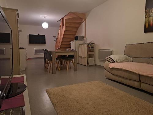 een woonkamer met een bank en een tafel bij Chambre privative dans un grand appartement in Langres