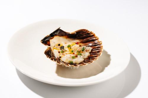 a oyster on a plate on a white plate at Hotel Hvala Superior - Topli Val in Kobarid
