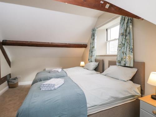 two beds in a bedroom with a window at The Old Haberdashery in Swanage