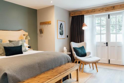 een slaapkamer met een bed, een stoel en een raam bij The Fox at Willian in Letchworth