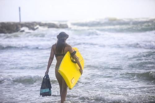 a woman walking on the beach with a yellow surfboard at Gwesty Gadlys Hotel in Cemaes Bay