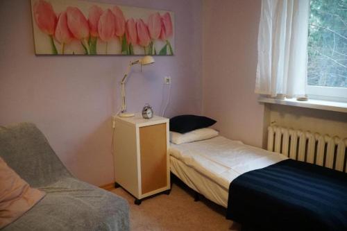 a bedroom with two beds and a lamp and a couch at Apartament Parterowy in Poznań