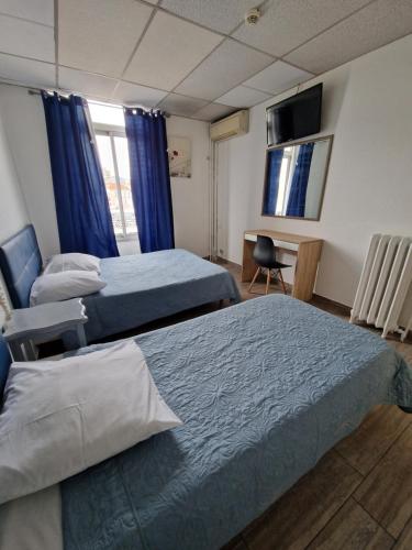 1 dormitorio con 2 camas y escritorio con ordenador en Hôtel du Nord en Cannes