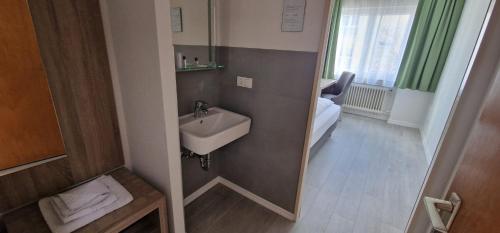 un piccolo bagno con lavandino e letto di Hotel Ladage a Francoforte sul Meno