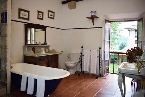 a bathroom with a tub and a toilet and a sink at Apartamentos Casona de Linares in Selaya