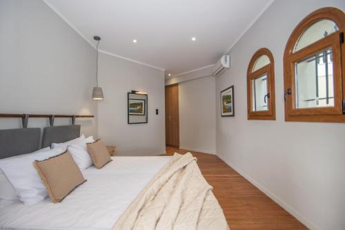 a bedroom with a large white bed and two windows at Adriana di Levante by "elite" in Ayios Kirikos