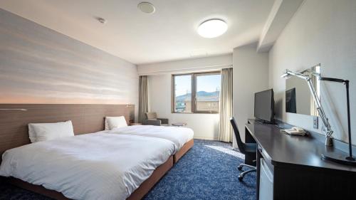 um quarto de hotel com uma cama, uma secretária e uma televisão em EN HOTEL Ise em Ise