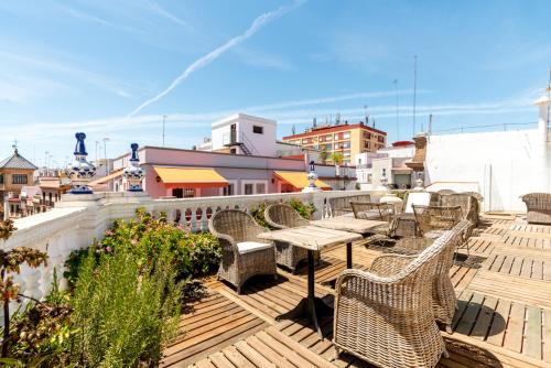 una terraza de madera con sillas y mesas en un edificio en Hostal Roomsole, en Sevilla