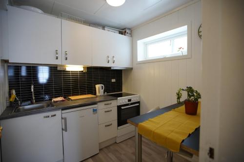 a kitchen with white cabinets and a table with a plant at Small apartment Havøysund in Havøysund