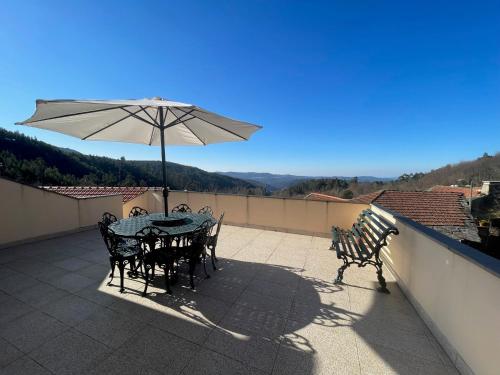 een tafel en stoelen met een parasol op een balkon bij Aroucanatur, Casa de Montanha in Arouca
