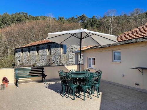 een tafel en stoelen met een parasol op een terras bij Aroucanatur, Casa de Montanha in Arouca