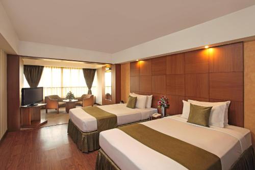 a hotel room with two beds and a television at Hotel Aurora Towers in Pune