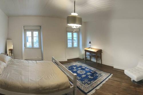 une chambre avec un lit, une table et des fenêtres dans l'établissement Les cloches de la Haye, à La Haye-Pesnel