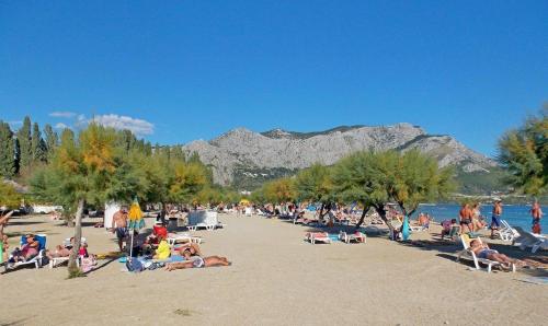 a crowd of people on a beach with mountains in the background at Apartments and Rooms Nikola in Omiš