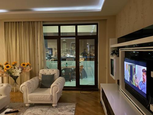 a living room with two chairs and a television at Park Azure Residence in Baku