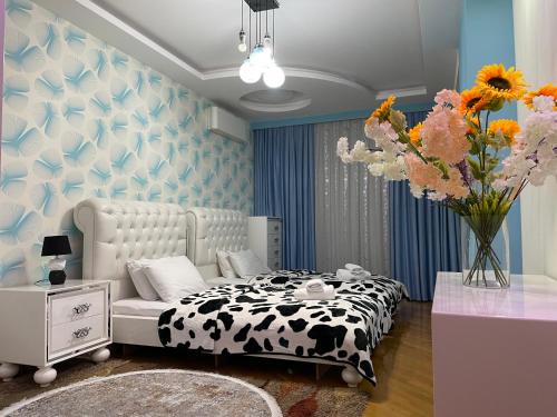 a bedroom with a black and white bed and a vase of flowers at Park Azure Residence in Baku