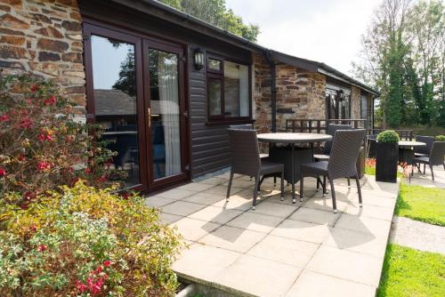 a patio with chairs and a table in front of a house at Trenython Manor Resort in Fowey