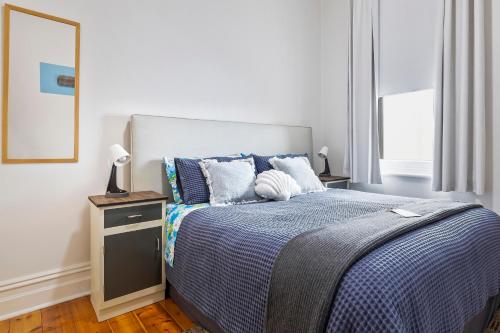 a bedroom with a bed with a blue comforter at Kerrigan's on Seaview- one minute walk to beach - not beachfront in Henley Beach