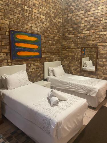 um quarto com duas camas e uma parede de tijolos em A Pousada Guesthouse em Nelspruit