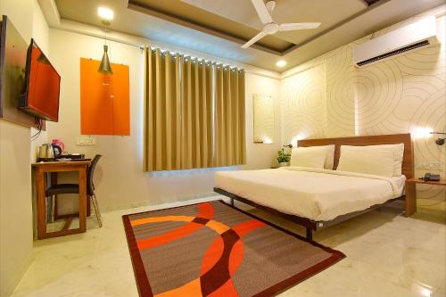 a bedroom with a bed and a television and a rug at FabHotel Manomay Stays I- Nagpur Airport in Nagpur