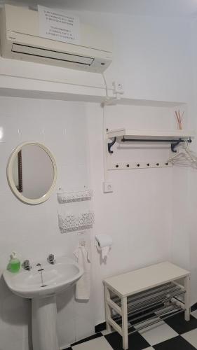 Baño blanco con lavabo y espejo en Pensión San Benito Abad, en Sevilla