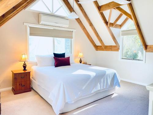 a bedroom with a white bed and two windows at Brigadoon Cottages in Haunted Hills