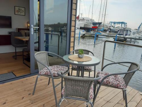 a table and chairs on a deck with a boat in the water at Hausboot Fjord Lyra mit Biosauna in Barth in Barth