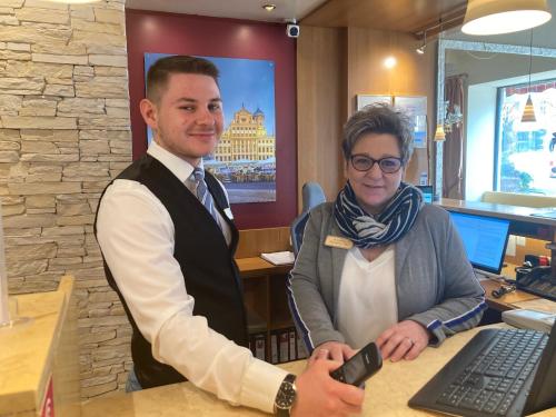 a man and a woman standing in front of a computer at City Hotel Ost am Kö in Augsburg