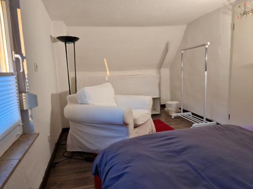 a living room with a white chair and a bed at Schönste Lage am Rhein, behagliches Haus mit Kamin. in Cologne