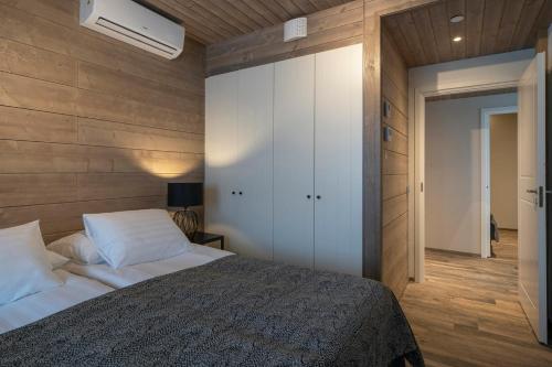 a bedroom with a bed and a wall with wood at Ski-Inn Kultakero in Pyhätunturi