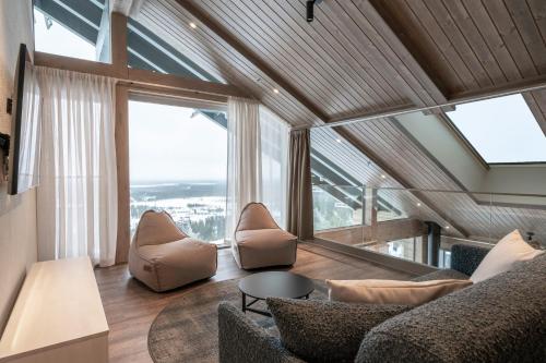 a living room with a couch and chairs and large windows at Ski-Inn Kultakero in Pyhätunturi