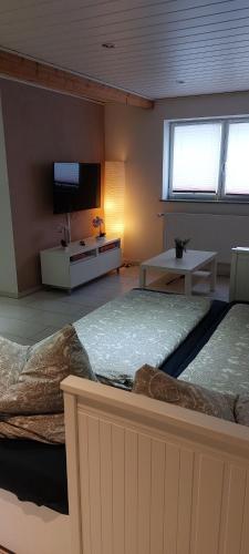 a room with two beds and a tv on the wall at Ferienwohnung/Monteurzimmer auf dem Bauernhof in Mörlenbach