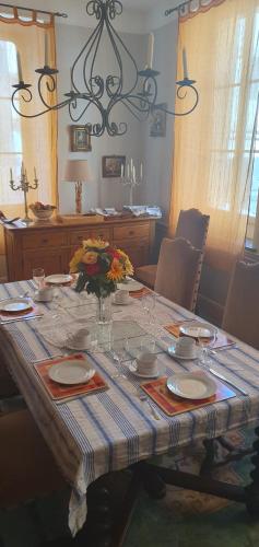 una mesa con platos y un jarrón de flores. en Maison Carrasserie, en Limoux