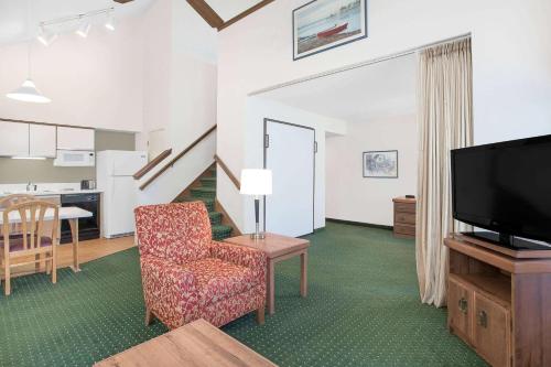 ein Wohnzimmer mit einem Stuhl und einem TV in der Unterkunft Hawthorn Extended Stay Hotel by Wyndham-Green Bay in Green Bay
