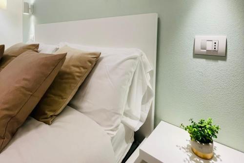 a white bed with pillows and a plant on a table at Ca' Ross in Formigine