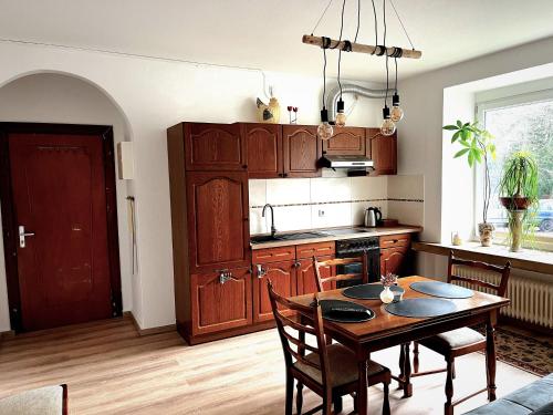una cocina con armarios de madera y una mesa con sillas. en Modern-Vintage Apartment, en Osterholz-Scharmbeck