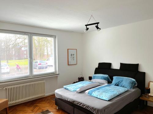 Un dormitorio con una cama con almohadas azules y una ventana en Modern-Vintage Apartment, en Osterholz-Scharmbeck