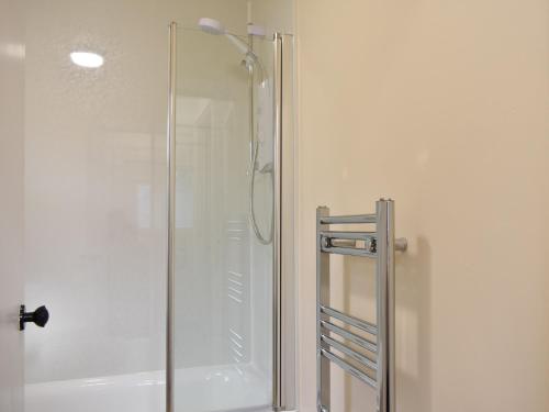 La salle de bains est pourvue d'une douche avec une porte en verre. dans l'établissement Rinnes Cottage, à Aberlour