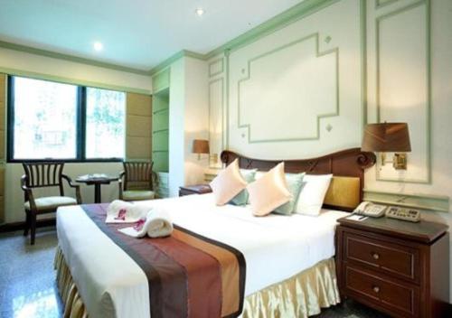 Habitación de hotel con cama grande y escritorio. en Majestic Suites Hotel en Bangkok