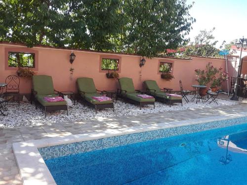 a pool with chairs and tables next to a house at Villa Diana Apartments in Skopje