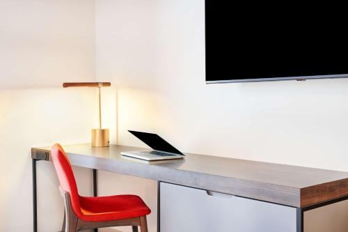 a desk with a laptop and a red chair at Hyatt Centric Downtown Denver in Denver