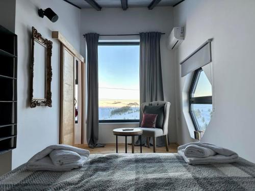 a bedroom with a bed and a chair and a window at HUUT in Zlatibor