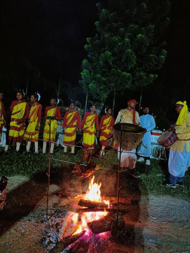 a group of people standing around a fire at night at Chocolate Inn Rainforest Resort & Spa in Jalpāiguri