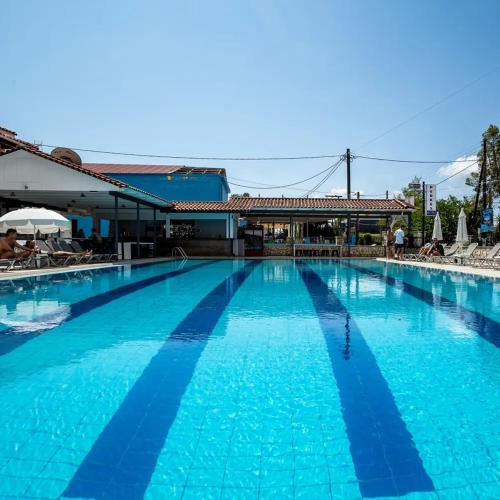 a large swimming pool with blue water in front of a building at Perkes Hotel Complex in Laganas