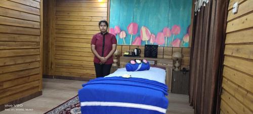 a man standing next to a bed in a room at Chocolate Inn Rainforest Resort & Spa in Jalpāiguri