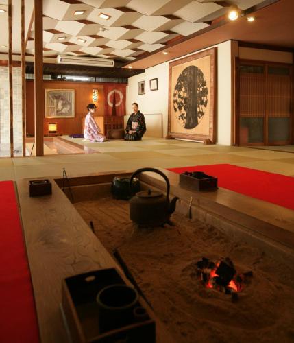 two people sitting in a room with a fire in the floor at Kaichoen in Yonago