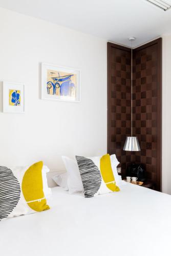 a bedroom with a white bed with yellow and black pillows at Hôtel Le Colisée in Paris