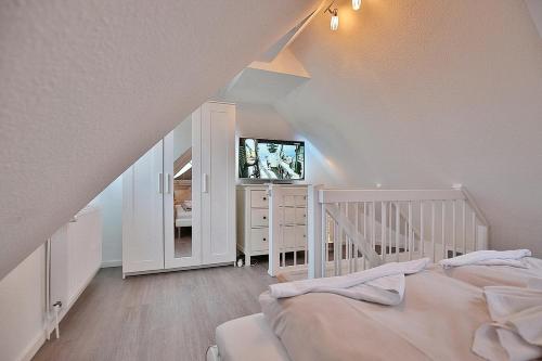 una camera da letto con una culla bianca e una TV in una stanza di Bädervilla Bergstraße 30 Bädervilla Bergstraße Appartement 9 a Timmendorfer Strand