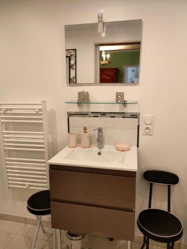 La salle de bains est pourvue d'un lavabo, d'un miroir et de deux tabourets. dans l'établissement La Maison des oliviers, à Aubeterre-sur-Dronne