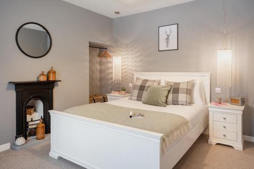 a bedroom with a large white bed and a mirror at Rose Cottage - Seasgair Lodges in Carrbridge